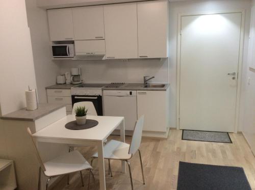 eine weiße Küche mit einem Tisch, Stühlen und einer Tür in der Unterkunft Kotimaailma Apartments Siljotie in Rovaniemi