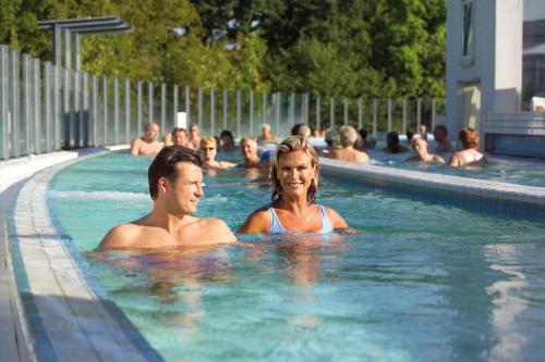 un hombre y una mujer en una piscina en Hotel Garni Hubertushof, en Bad Füssing