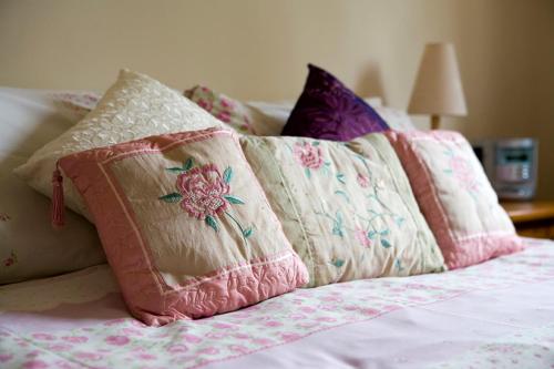 un montón de almohadas sentadas encima de una cama en Nethercote Cottage, Seven Springs Cottages, en Cheltenham