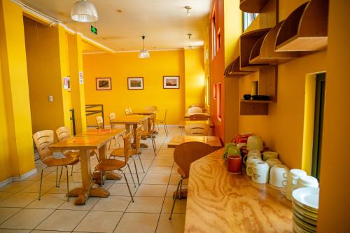 ein Restaurant mit Tischen und Stühlen und gelben Wänden in der Unterkunft Ayelen Express in Calama
