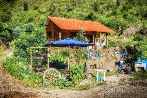 a house with an umbrella and a sign in front of it at Unique Tiny House with Natural Building Techniques in Figueiró dos Vinhos