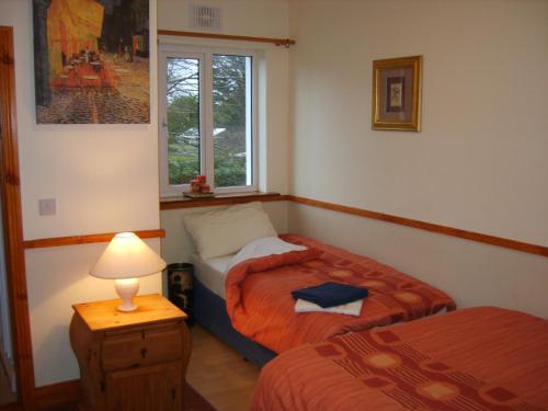 a bedroom with two beds and a lamp and a window at Killarney Railway Hostel in Killarney