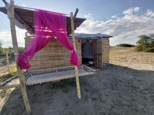 a wooden cabin with a pink curtain in front of it at biohotel tatacoa Qji in Villavieja