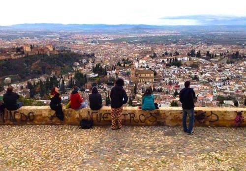 a group of people sitting on a bench overlooking a city at ECO Hostel in Granada