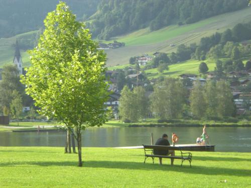 two people sitting on a park bench next to a lake at Haus Knapp FeWo Gastein in Dorfgastein