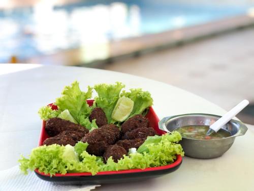 a red plate of food with lettuce and meatballs at Pousada Capyvara in Arenápolis
