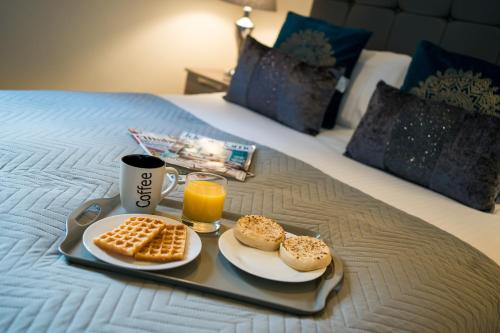 a tray of food with biscuits and orange juice on a bed at Church View Irene Court Cockermouth in Cockermouth