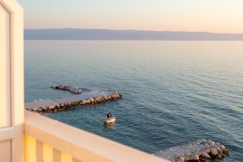 a man in a boat in the water from a balcony at Apartments Antonio - Podstrana, Split in Podstrana