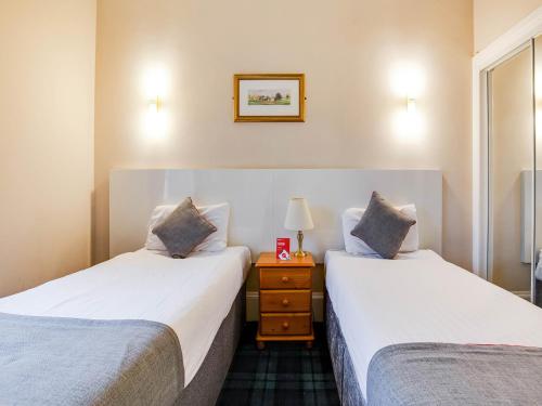two twin beds in a room with a night stand at Lost Guest House Stirling in Stirling