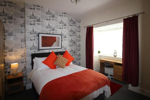 a bedroom with a bed with red pillows and a window at Spacious House in Cleethorpes - sleeps 10 in Cleethorpes