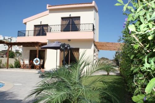 a house with a balcony and an umbrella at Holidays Villas in Pissouri
