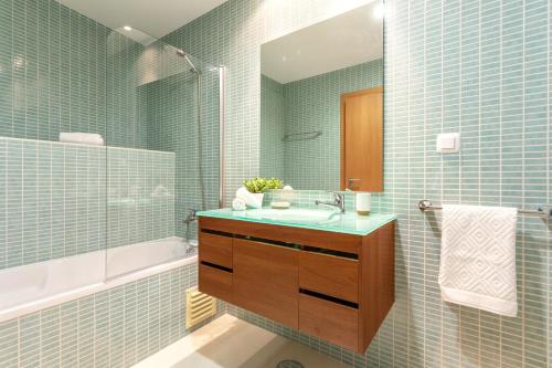 uma casa de banho com paredes em azulejos azuis, um lavatório e uma banheira em Privilege Apartment Galichet with Rooftop Pool, Village Marina - Olhão em Olhão