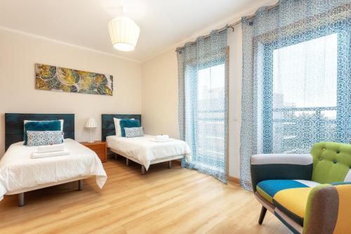um quarto com duas camas e um sofá e uma janela em Privilege Apartment Galichet with Rooftop Pool, Village Marina - Olhão em Olhão