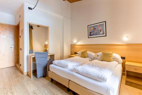 a bedroom with a large white bed and a desk at Hotel Derby in Folgarida