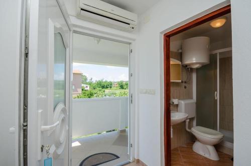 een badkamer met een douche, een toilet en een raam bij Holiday S&M in Lopar