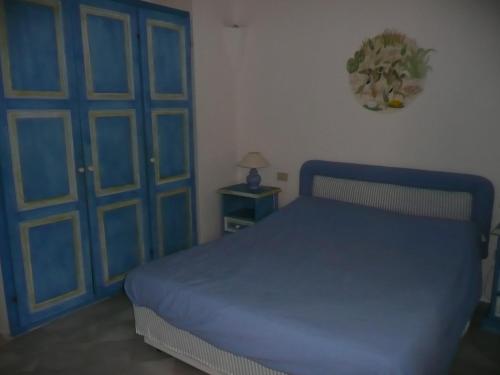 a bedroom with a blue bed and a blue door at Cormorani Alti in Baja Sardinia