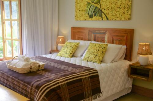 a bedroom with a bed with a basket on it at Pousada Vila do Loro in Domingos Martins