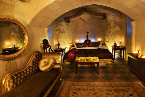 een slaapkamer met een bed en een bank in een kamer bij Cappadocia Perimasali Cave Hotel in Urgup