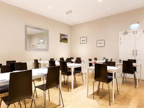 a dining room with white tables and black chairs at Lost Guest House Stirling in Stirling