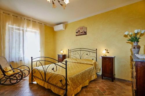 a bedroom with a bed and a chair and a window at Agriturismo MonteCrespini in Saturnia