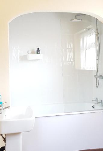 a white bathroom with a sink and a mirror at Beautiful 4 bedroom Victorian Apartment Sleeps 7 STOCKPORT in Manchester