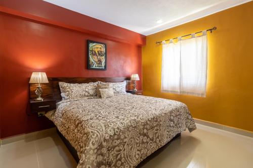 ein Schlafzimmer mit einem Bett mit orangefarbenen Wänden und einem Fenster in der Unterkunft PRIME VILLAGE Cozumel in Cozumel