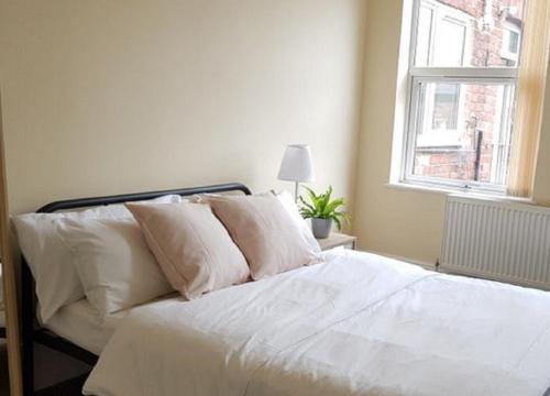 a white bed with white pillows and a window at Beautiful 4 bedroom Victorian Apartment Sleeps 7 STOCKPORT in Manchester
