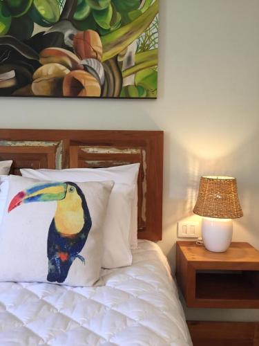 a painting of a bird on a pillow next to a bed at Pousada Vila do Loro in Domingos Martins