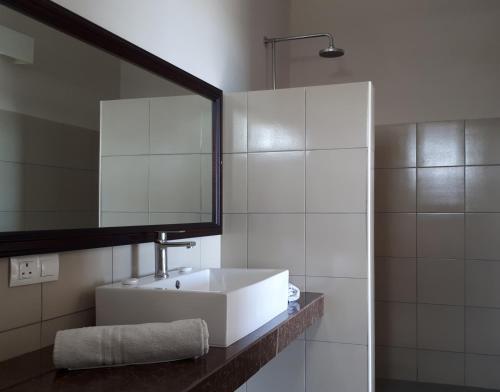 een badkamer met een witte wastafel en een spiegel bij Résidence Riva Bella in Port Louis