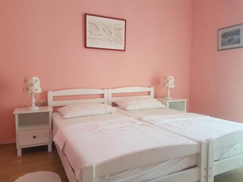 2 camas num quarto com paredes cor-de-rosa e 2 candeeiros em Hotel Palace Vrkljan em Karlobag
