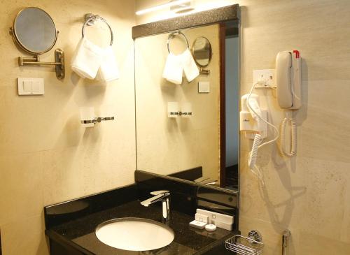 a bathroom with a sink and a mirror and a phone at Daamat Hotel in Addis Ababa
