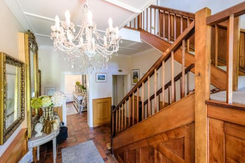 a dining room with a staircase and a chandelier at Oude Berg Guesthouse - 10 Caledon Street in George