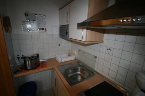 een kleine keuken met een wastafel en een magnetron bij Ferienhaus Breithaupt in Cuxhaven