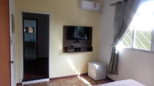 a bedroom with a tv on the wall and a window at POUSADA LOS AMIGOS CAMPECHE in Florianópolis