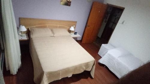 a bedroom with a white bed and two night stands at POUSADA LOS AMIGOS CAMPECHE in Florianópolis