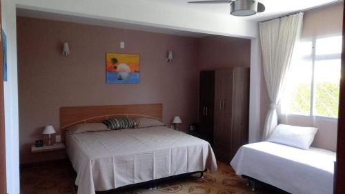 a bedroom with a white bed and a window at POUSADA LOS AMIGOS CAMPECHE in Florianópolis