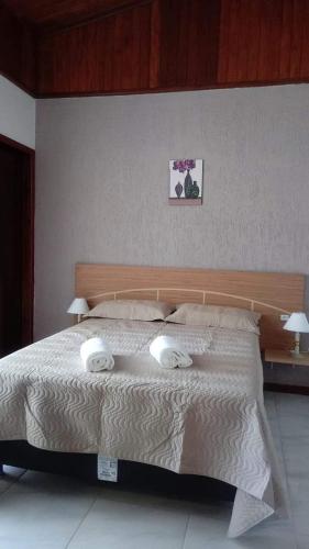 a bedroom with a large bed with two towels on it at POUSADA LOS AMIGOS CAMPECHE in Florianópolis