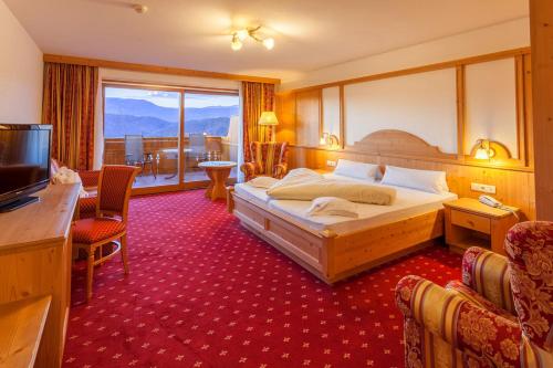 een hotelkamer met een bed en een groot raam bij Hotel Rosslaufhof in Castelrotto