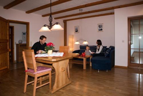 a group of people sitting at a table in a living room at Jakobsbauernhof in Freiamt