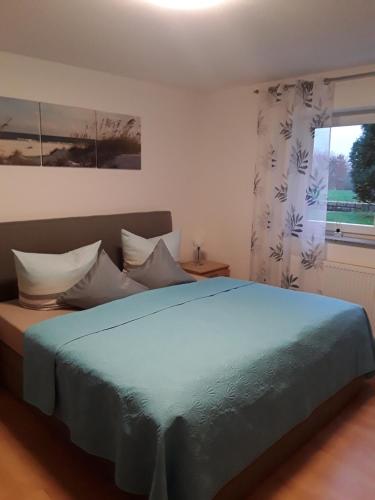 um quarto com uma cama azul e uma janela em Ferienwohnung Mayer em Kirchheim am Ries