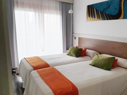 
a hotel room with two beds and two windows at Sandos Benidorm Suites in Benidorm

