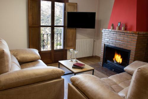 a living room with two couches and a fireplace at Puerta Bubión Apartamentos in Bubión