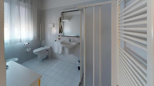 bagno bianco con servizi igienici e lavandino di Hotel Villa Sorriso a Lido di Jesolo