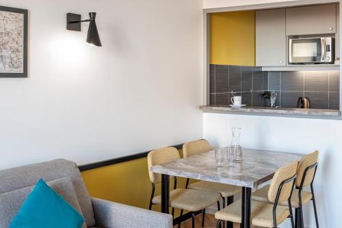 a kitchen and dining room with a table and chairs at Aparthotel Adagio Paris Montrouge in Montrouge