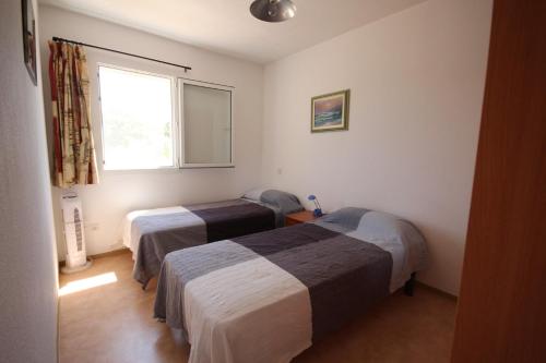 une chambre avec deux lits et une fenêtre dans l'établissement Belle villa d angle avec veranda et WIFI, 2 chambres dans résidence sécurisée avec piscine commune 800m de la mer Un vrai Havre de Paix LRCS116, à Portiragnes