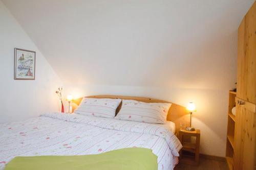 a bedroom with a white bed with two pillows at Ferienwohnung Stockrose in Middelhagen