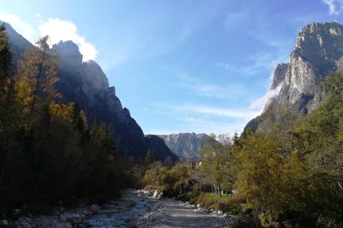 a river in a canyon with mountains in the background at Sweet Dolomites Sauna & Jacuzzi in Agordo