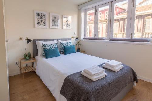 a bedroom with a large white bed with towels on it at Oporto Between Walls by the center with A/C in Porto