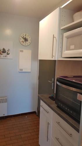 uma cozinha com armários brancos e um micro-ondas em Appartement T1 central pour cures courts séjours em Saint-Paul-lès-Dax