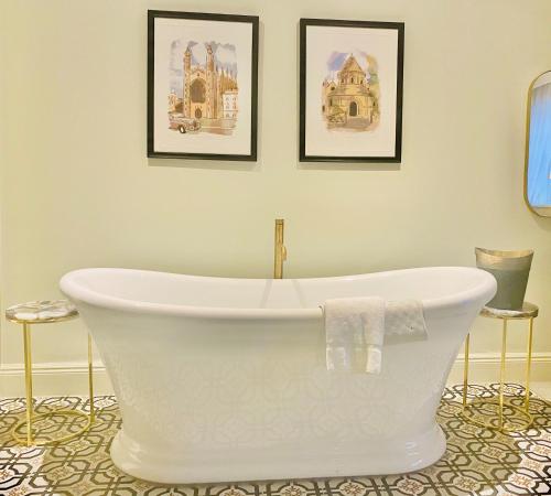a white bath tub in a bathroom with two pictures on the wall at Gonville Hotel in Cambridge